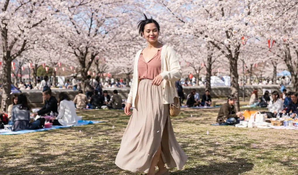 Mulher brasileira sorrindo sob cerejeiras floridas durante um encontro de Hanami no Japão