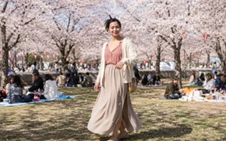 Mulher brasileira sorrindo sob cerejeiras floridas durante um encontro de Hanami no Japão