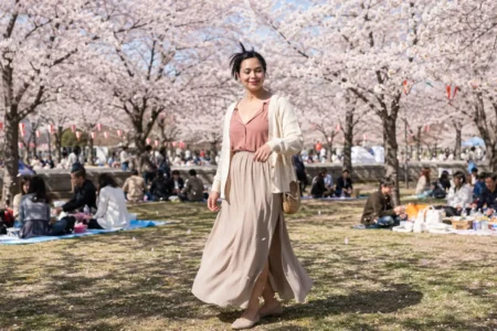 Mulher brasileira sorrindo sob cerejeiras floridas durante um encontro de Hanami no Japão