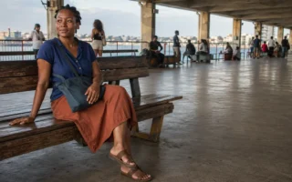 Mulher jovem sentada em terminal hidroviário brasileiro, tranquila e presente enquanto aguarda o embarque.