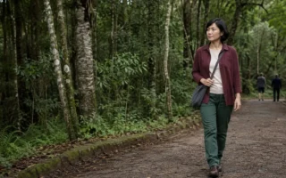 Mulher jovem caminhando com calma entre árvores em um parque de Mata Atlântica no Brasil